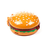 Angled view of an orange plastic hamburger truck action toy. It features a rounded bun with white sesame seeds, distinct brown, red, and green layers, and a small red latch on the side.