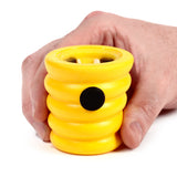 Close-up of a yellow beehive-shaped pop out toy held in hand, featuring a ridged body and a black circular button.