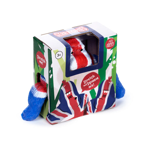 Angled view of a white, red, and blue Union Jack gorilla stretchy stress fidget toy, partially visible inside a green-patterned display box, with its blue limbs protruding from the sides.