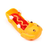 Angled view of a yellow hot dog sausage dog fidget toy with a red sausage body and yellow mustard zig-zag, lying on its back with its face and spotted white paws visible.