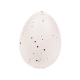 Upright speckled white hatching egg toy, featuring irregular dark spots and a small hole at its top.