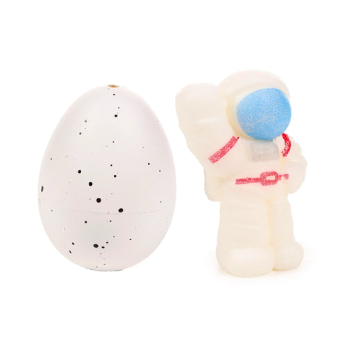 White speckled hatching egg and a white astronaut toy with a blue visor and red uniform details, displayed side-by-side.