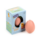 Angled view of a Capybara Hatching Egg Toy. A light blue retail box, featuring 'Hatching Egg Capybara' text, a cartoon capybara, and instructions, is shown next to a plain light peach coloured hatching egg.