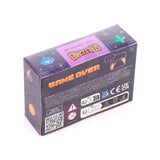 Angled view showing the top and side of the dark blue packaging box for a Stretchy Stress Fidget Toy - Game Over Game Controller. The box features pixelated video game controller graphics, with 'GAME OVER' and 'STRETCHIES' text, alongside multilingual safety warnings and a '3+' age rating.