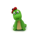 Close-up of a bright green stretchy Nessie fidget toy with large white eyes, a beige belly, and a red flat cap with a black pom-pom.