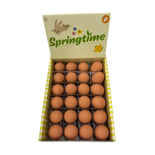 Overhead view of an open display box filled with numerous brown bouncy eggs. The box lid features 'Springtime' text, a bunny, chick, and flowers, with yellow and white checkered sides.