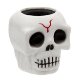 Angled view of a white pop out toy skull with black eye sockets and nose, a red mark on its forehead, and an open top revealing a dark interior.