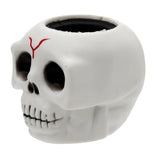 Angled view of a white skull pop out toy with black eye sockets, nose cavity, and an open black top, featuring a red marking on its forehead and visible teeth.