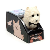 Angled view of a white West Highland Terrier stretchy fidget toy with a black bow tie, emerging from its black cardboard packaging featuring a cartoon Westie and Stretch and Squeeze text.