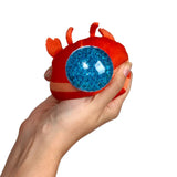 Orange lobster fidget toy with a blue bead-filled eye, being squeezed by a hand.