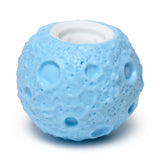 Angled view of a light blue pop out toy planet with a textured, cratered surface and a white opening at the top.