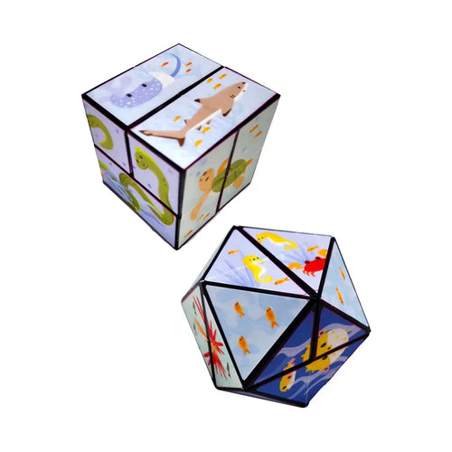 Angled view of two puzzle cubes. One cube displays marine illustrations of a shark, a manta ray, an eel, and a turtle on light blue panels. The other cube, reconfigured into a multi-faceted shape, features yellow seahorses, a red crab, and various fish. Both cubes have black borders.