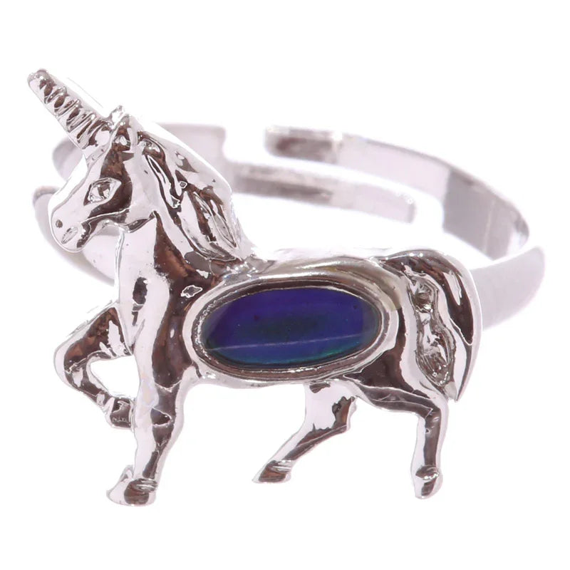 Close-up angled view of a silver-coloured unicorn design mood ring, featuring an oval mood stone displaying deep blue and greenish-blue colours, with an adjustable band.