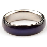 Close-up, angled view of a mood ring with a glossy, dark purple outer band and a shiny silver-coloured inner band.