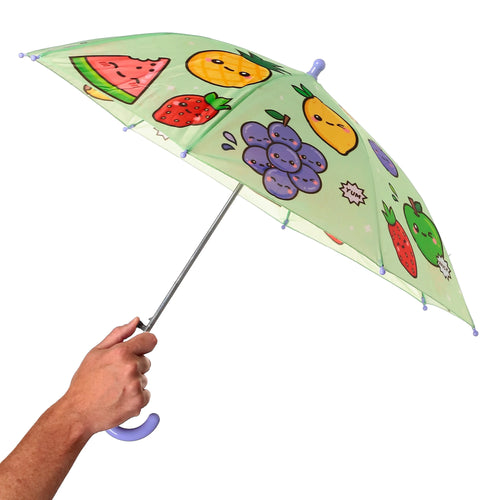 Angled view of a child's umbrella, held in hand, featuring a light green canopy with cheerful cartoon fruit characters. Visible are smiling watermelon, pineapple, strawberry, apple, and grape designs, and the purple curved handle.