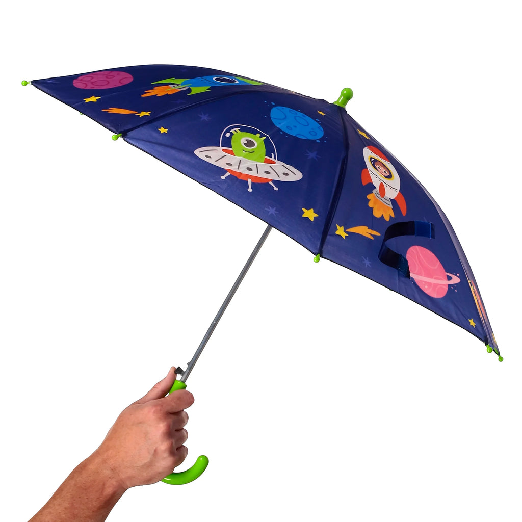 Angled view of an open navy blue kids' space umbrella, depicting a green alien in a flying saucer, a rocket ship, and colourful planets. It features a bright green curved handle, held by a hand.