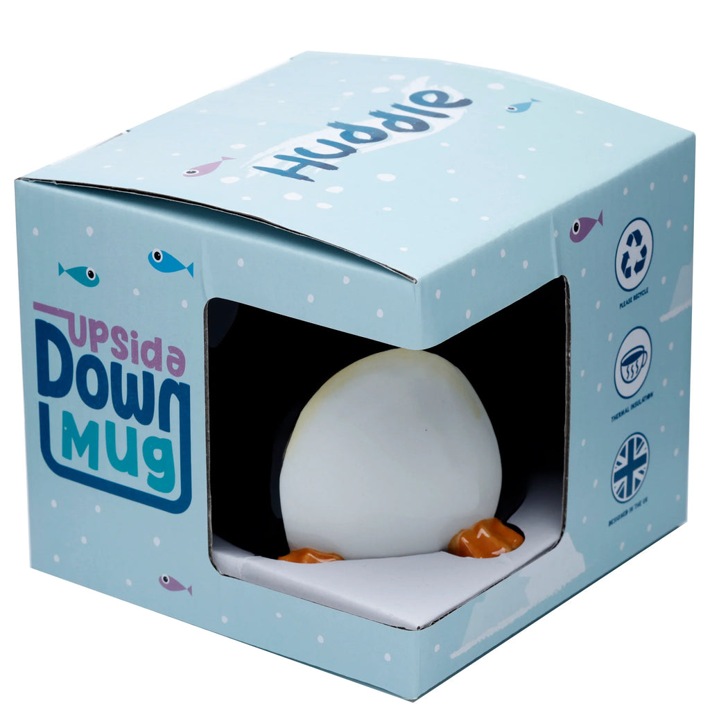 Angled view of a Huddle Penguin Upside Down Ceramic Shaped Mug, featuring its white belly and orange feet visible through a cut-out in its light blue retail packaging.