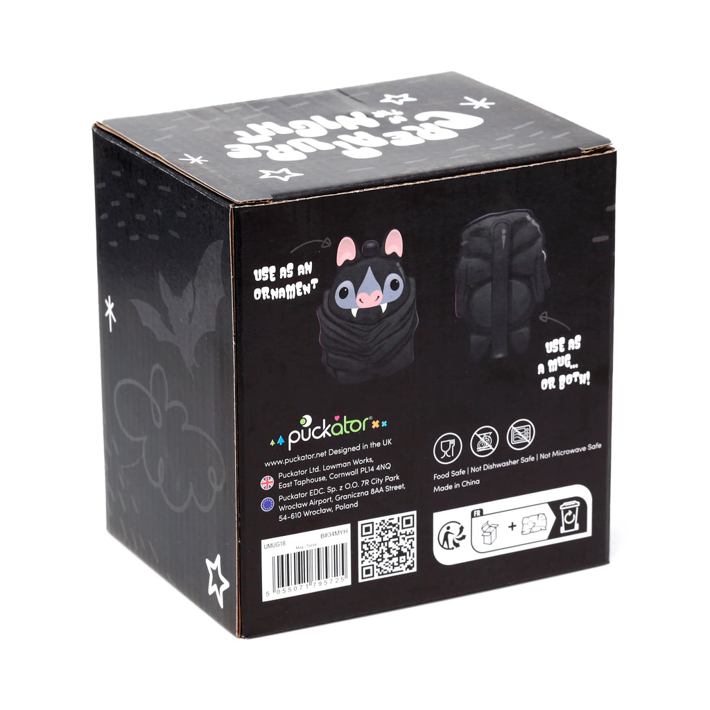 Angled view of a black packaging box for a bat novelty mug. The box features a cartoon illustration of a grey and black bat with pink ears, white fangs, and text indicating its use as an ornament or mug. Product details such as 'Food Safe' and a barcode are also visible.