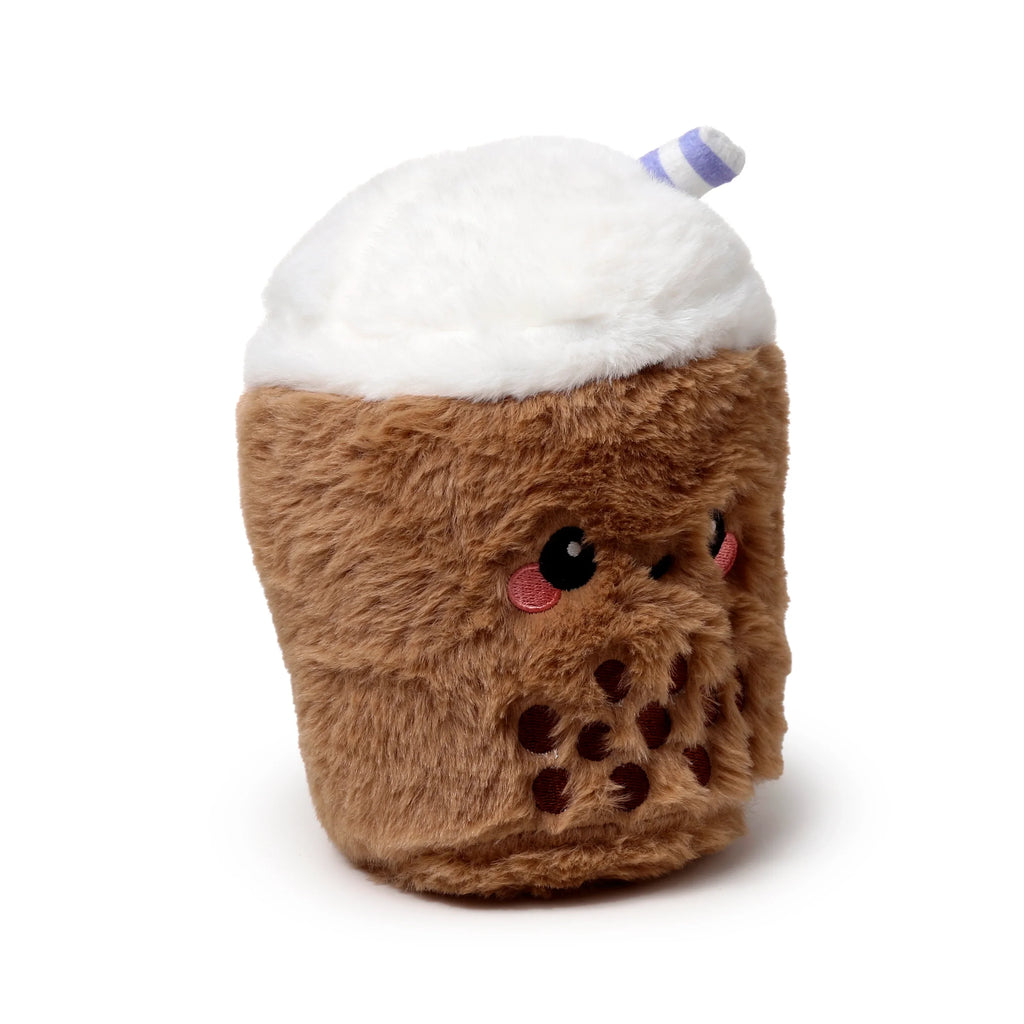 Angled view of a brown and white plush bubble tea heat pack, featuring an embroidered cute face, dark brown tapioca pearls, and a white and purple striped straw.