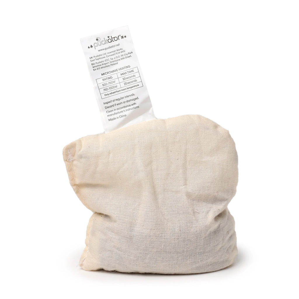 Angled view of a natural beige fabric microwavable heat pack pouch, with a white instruction label showing microwave heating times.