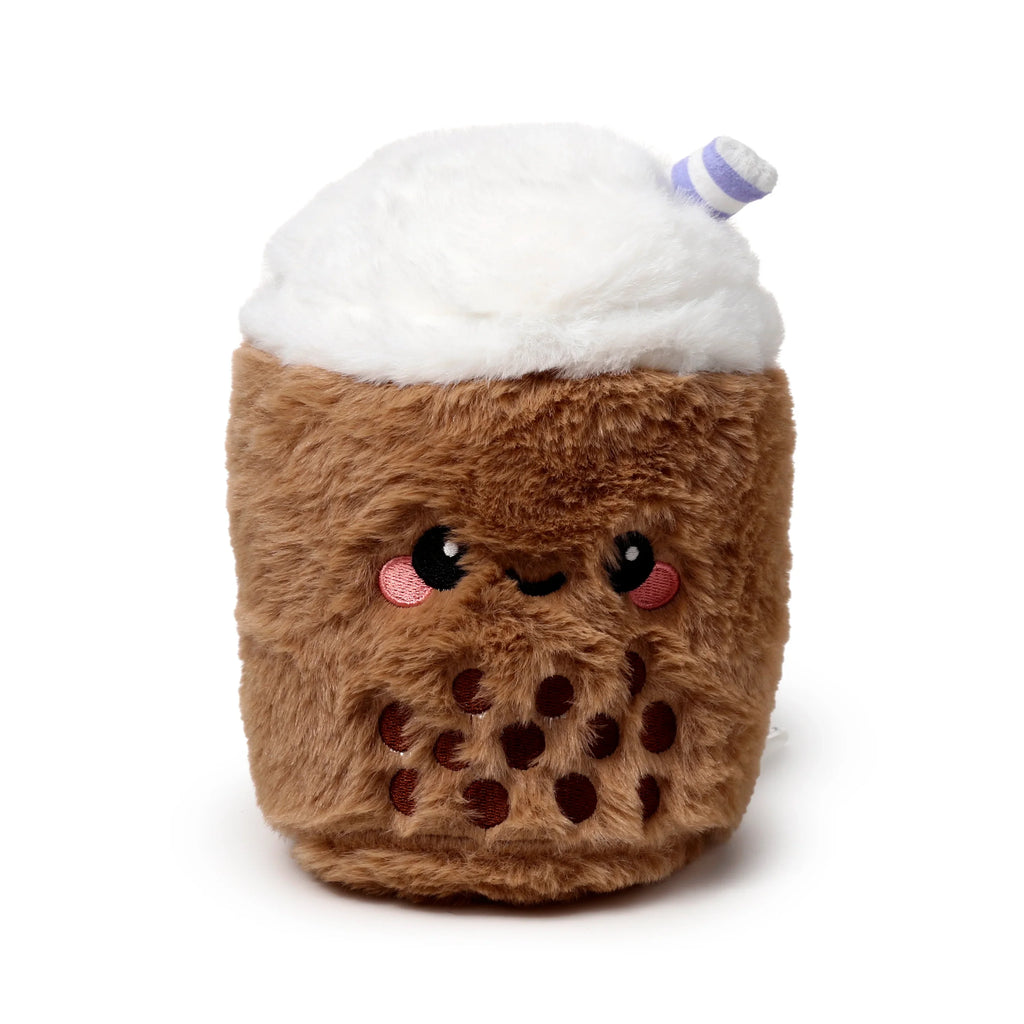 Front view of a plush microwavable heat pack in a bubble tea design, featuring a brown fuzzy body, white fluffy top, a cute embroidered face with pink cheeks, and a purple and white striped straw.