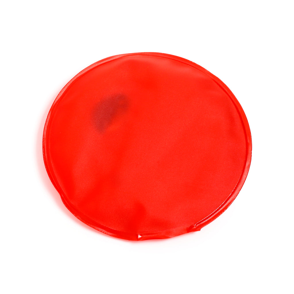 Overhead view of a circular red hand warmer, featuring a smooth surface and sealed edges.