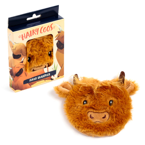 Angled view of a plush, furry brown Highland Coo hand warmer with embroidered features, positioned beside its open, illustrated product box showing a window, 'HAIRY COOS' and 'HAND WARMER' text.