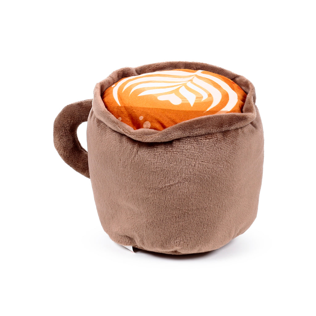 Brown plush microwavable heat pack designed as a cappuccino mug, featuring an orange-brown top with white latte art and a visible handle.