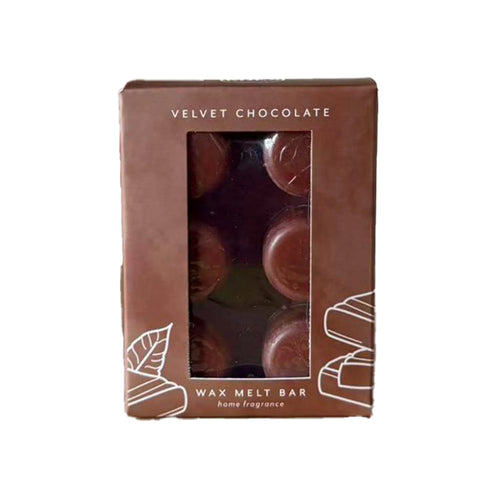 Front view of a brown box labelled 'Velvet Chocolate' with white leaf and stacked bar illustrations. Six dark chocolate-coloured circular wax melts are visible through a clear window, above the text 'WAX MELT BAR home fragrance'.