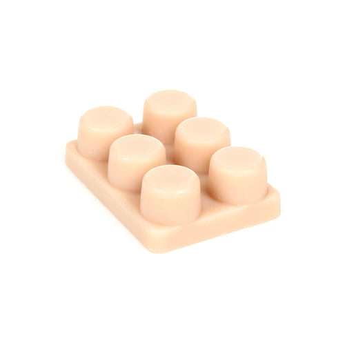 Angled view of a creamy peach wax melt block with six rounded segments.