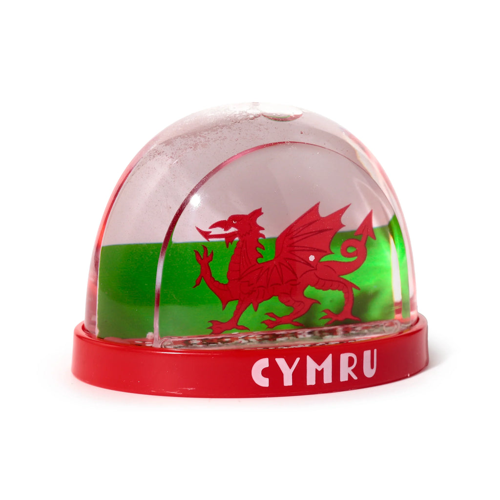 Front view of a collectable snow globe featuring a red Welsh dragon against a green and white background, with 'CYMRU' embossed in white on the red base.