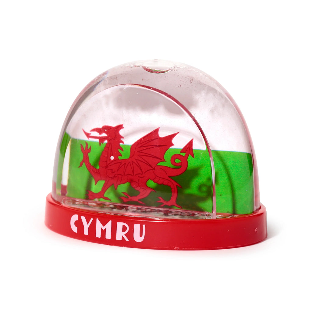 Front view of a Welsh Dragon snow globe, featuring a red dragon silhouette and green background within the clear dome, atop a red base with white 'CYMRU' lettering.