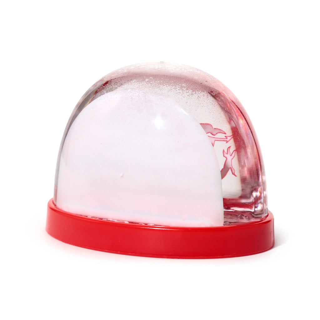Angled view of a Welsh Dragon snow globe with a red base, clear dome, and a dense white snow storm effect inside.