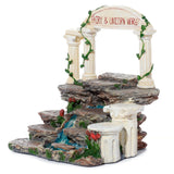 Fairy & Unicorn World Figures Display Stand, front angled view of a tiered rocky structure with an arched gateway, white pillars with green vines, a blue waterfall, and red floral details.