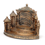 Ornate bronze display stand with green accents, featuring a temple-like design with tiered steps, decorative columns, and a textured background, shown from a front-angled perspective.