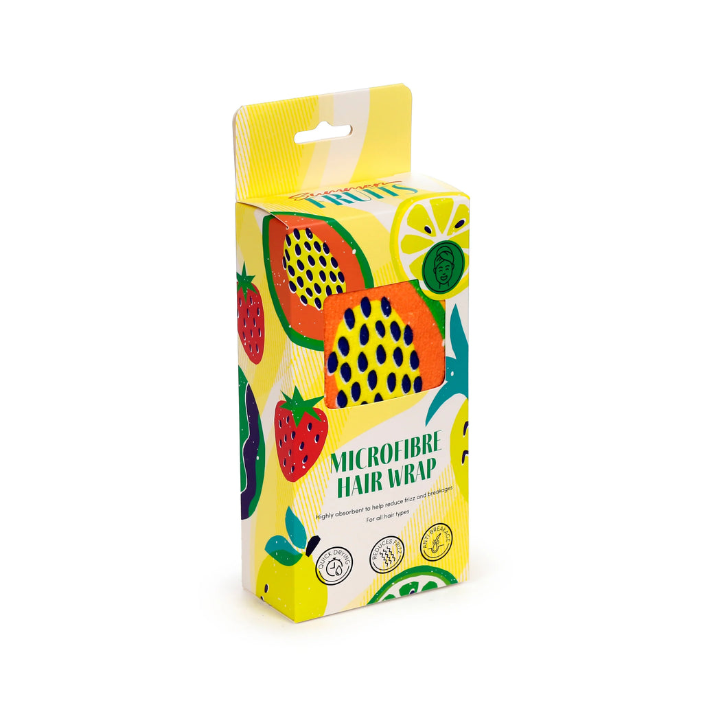 Angled view of a microfibre hair wrap towel in colourful 'Summer Fruits' packaging, featuring illustrations of papaya, strawberry, and lemon on a yellow box with a hang tab, and a glimpse of the orange towel visible through a cutout.