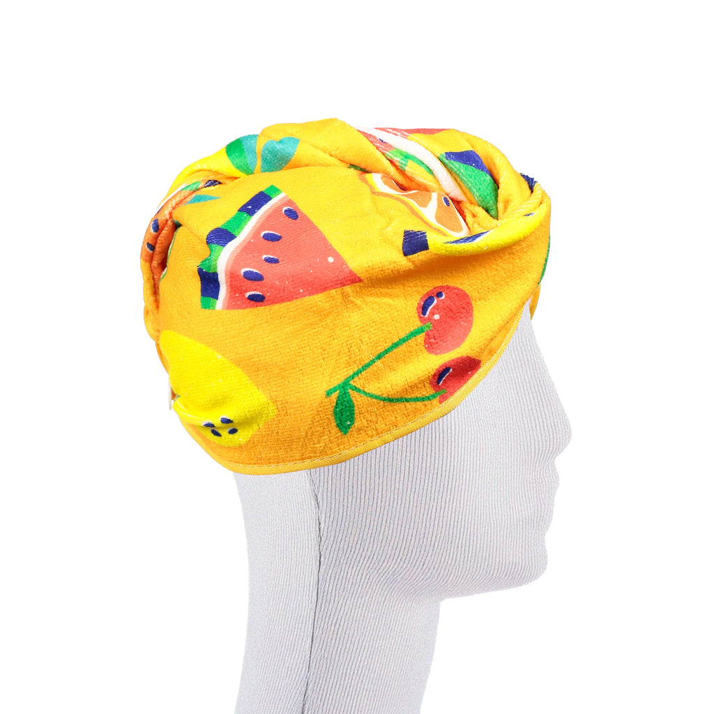 Side view of a yellow hair wrap towel with a colourful summer fruits pattern, depicting watermelon and cherries, on a mannequin head.