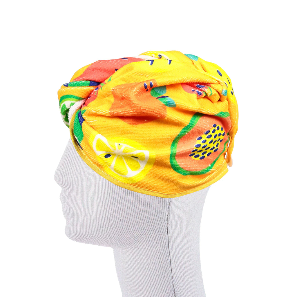 Side profile of a yellow hair wrap towel featuring a vibrant summer fruits pattern, including lemon and papaya designs, on a white mannequin head.