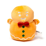 Front view of a ginger-coloured plush gingerbread man toy with white embroidered facial features and icing details, a red bow tie, and three green buttons.