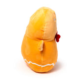 Side view of a 'Squidglys' Christmas gingerbread man plush toy, orange with a stubby arm, white icing detail, and a red bow.