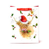 Front view of a white Christmas gift bag depicting a shaggy Highland coo wearing a red Santa hat and eating green holly leaves. The bag has red ribbon handles and a round tag showing a small coo.