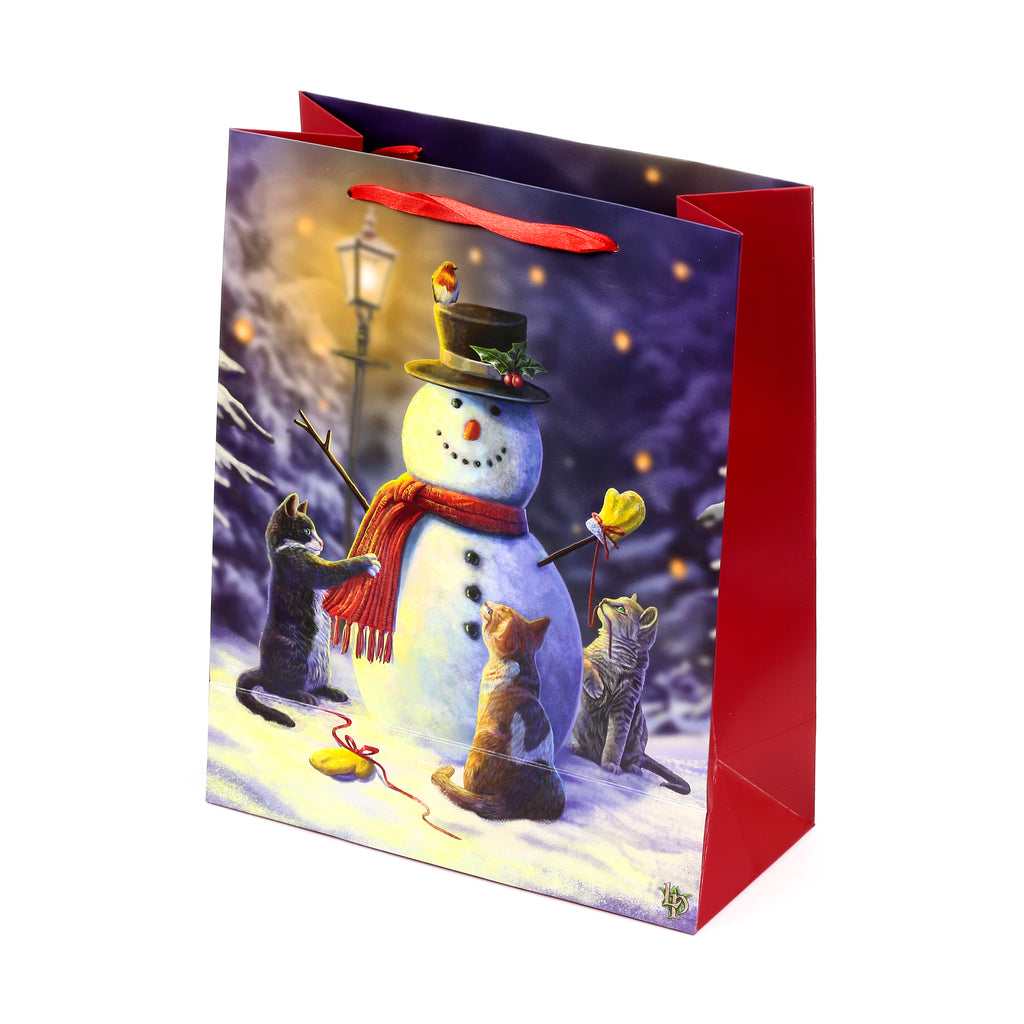 Large Christmas gift bag, angled view, showcasing a festive illustration of a snowman, three cats playing in snow, a robin, and a lamppost, with red fabric handles and red side panels.