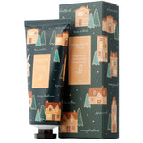 Angled front view of a dark green 75ml Moisturising Hand Cream tube and matching rectangular gift box, both featuring a festive Christmas gingerbread lane design with brown and orange gingerbread houses, green Christmas trees, and small yellow stars, clearly displaying the 'Gingerbread Moisturising Hand Cream 75ml' label.