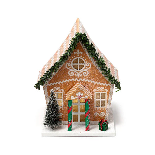 LED Christmas gingerbread house decoration, front view, featuring a frosted roof with green garland, white icing details, glowing windows, a miniature Christmas tree, and a small green gift on its white base.