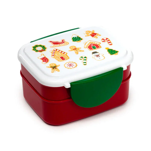 Elevated angled view of a red and white bento clip lock lunch box. The white lid is adorned with colourful Christmas illustrations, including gingerbread men, gingerbread houses, trees, candy canes, snowmen, and a sleigh. Green clips secure the sides.