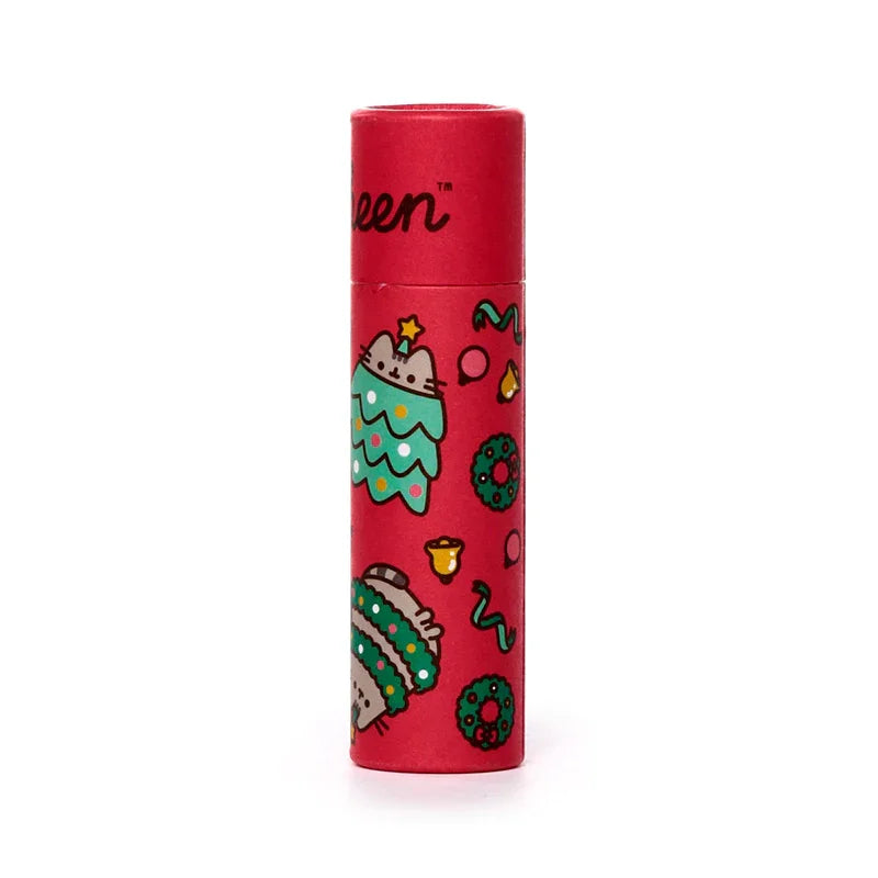 Front view of a red cylindrical paper stick lip balm featuring Christmas-themed illustrations, including Pusheen the Cat as a festive tree and wrapped in green garland, surrounded by small wreaths and bells.