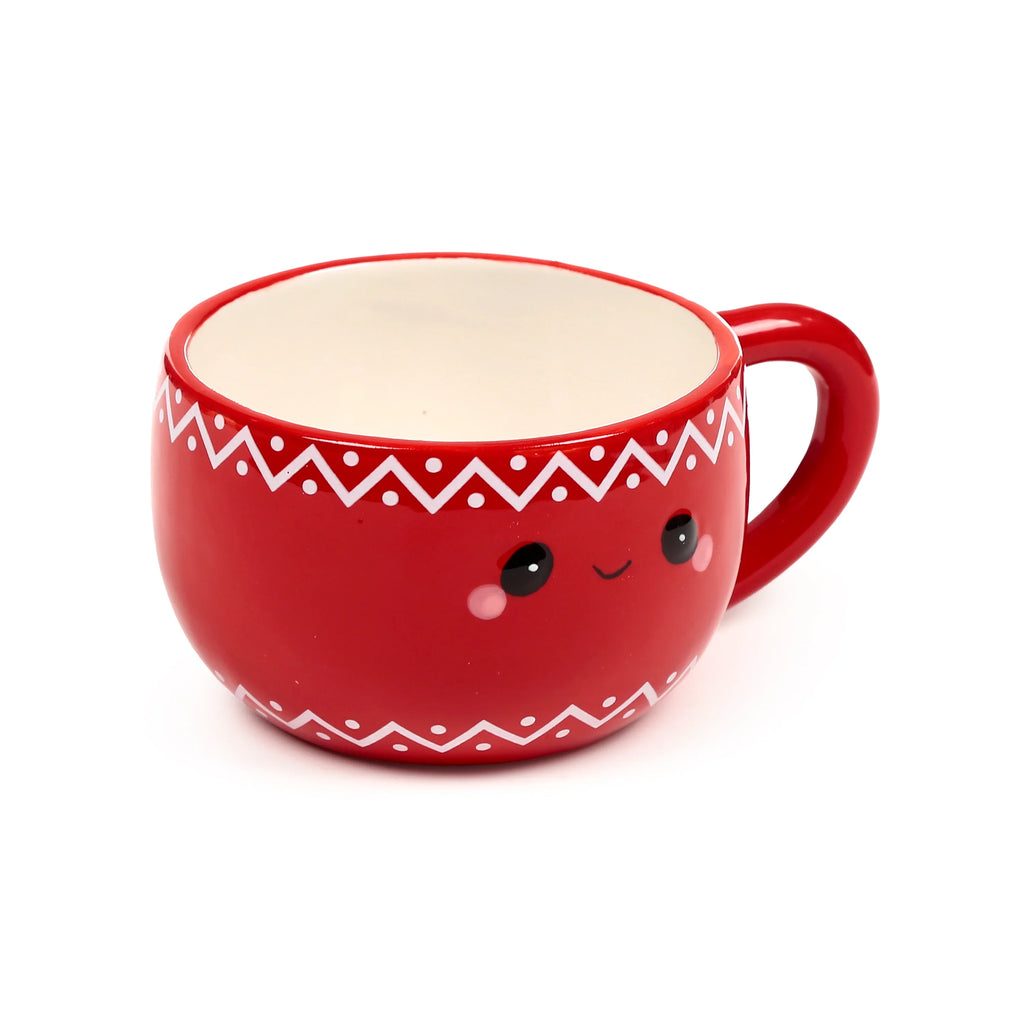 Angled view of a red ceramic mug with a cute cartoon face, featuring black eyes, a small smile, and pink cheeks. The mug has white zigzag and dot patterns around the rim and base, and a matching red handle, with a white interior.