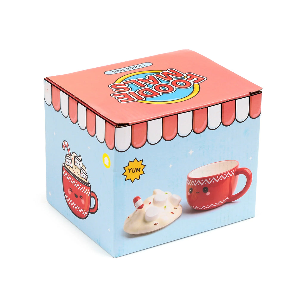 Angled view of the 'Foodiemals' ceramic lidded mug product box. The light blue packaging illustrates a happy red mug, one filled with hot chocolate, marshmallows, and a candy cane, and another showing the mug with its separate cream-coloured, marshmallow-shaped lid. The pink box top is visible, featuring 'FOODIEMALS LIDDED MUG' text.