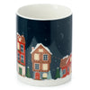 Angled view of a porcelain mug with a white interior rim. Its dark blue exterior features a festive Christmas village scene, depicting colourful houses with illuminated windows, snow-covered ground, Christmas trees, a crescent moon, and stars in the night sky.