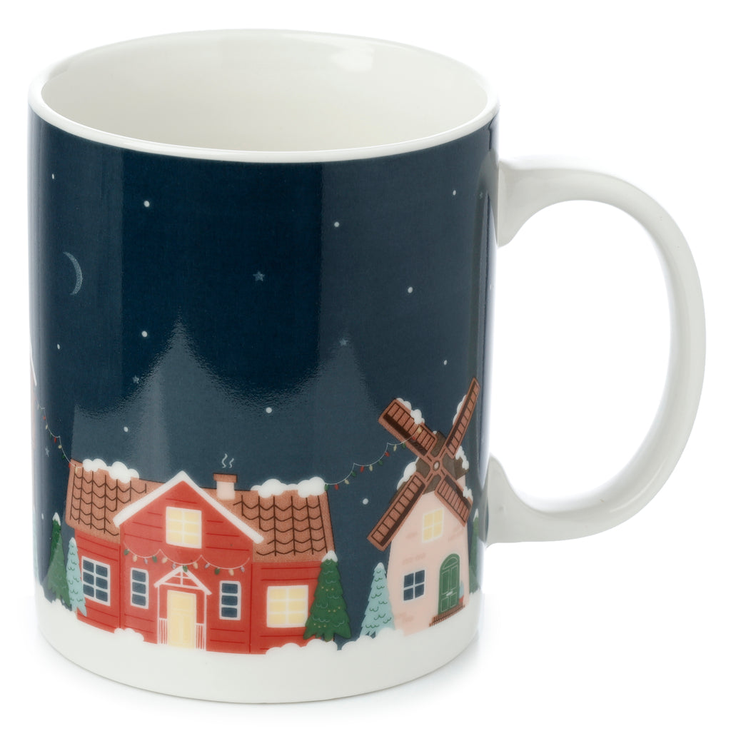 Porcelain mug depicted at an angle, showcasing a Christmas village design with red and pink houses, green trees, snow, and colourful festive lights under a dark blue starry sky with a crescent moon; includes the white handle.